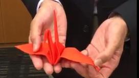 Красный журавлик оригами в руках