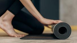Девушка сворачивает коврик для йоги