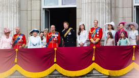 Члены королевской семьи стоят на балконе дворца