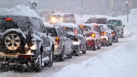 Машины едут по дороге в снегопад