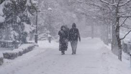 Люди идут под снегопадом в Алматы