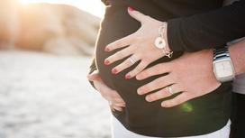 Женские и мужские руки на животе беременной