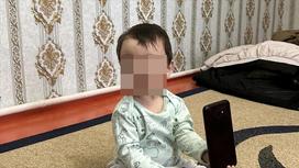 Мальчик сидит на ковре с телефоном