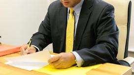 Мужчина в костюме подписывает документ