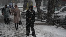 Люди идут по улице в снегопад
