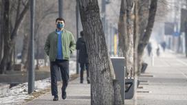 Мужчина в синей маске идет по улице на фоне деревьев