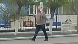 Мужчина идет по улице с плакатами в руках