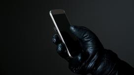 Рука в перчатке держит мобильный телефон