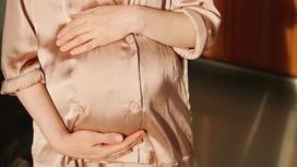 Беременная женщина держит свой живот