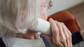 Пожилая женщина держит в руке телефон