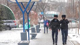 Двое полицейских идут по улице в снегопад