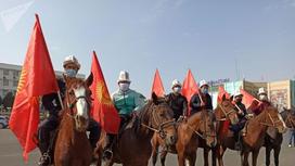 Всадники на лошадях держат флаг Кыргызстана