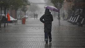 Девушка прячется от дождя под  зонтом