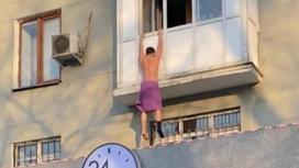 Мужчина висит на балконе в розовом полотенце и одном носке