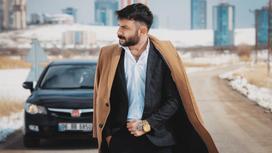 Мужчина в костюме и пальто на фоне машины и небоскребов