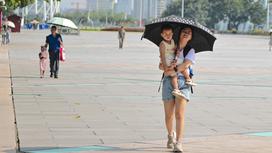 Мама с ребенком на руках идет под зонтом
