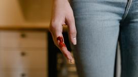 Женщина с кровью на пальце