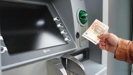 Держатель банковской карты снимает в банкомате деньги