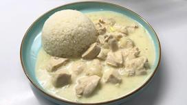 На сервировочной тарелке курица в сметанном соусе и рис