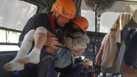 Спасатель держит на руках спасенную девочку