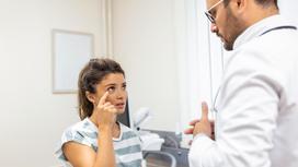 Девушка показывает доктору, где у нее болит глаз