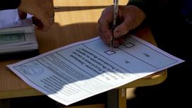 Человек подписывает бланк для голосования