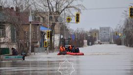 Спасатели плывут на лодке по затопленной улице