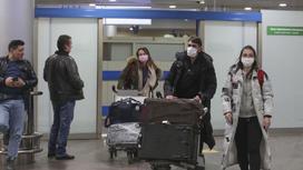 Пассажиры в масках везут багаж в аэропорту