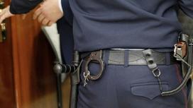Полицейский в форме со спины с пистолетом и наручниками