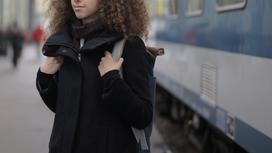 Девочка с рюкзаком стоит возле поезда