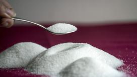 Ложка сахара и сахар-песок, рассыпанный на столе