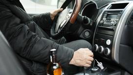 Мужчина сидит за рулем авто, рядом с ним стоит бутылка спиртного