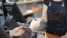 Продавец принимает оплату на кассе у покупателя с помощью банковской карты