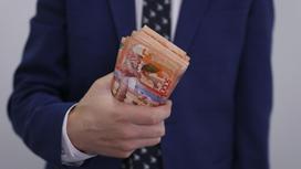Мужчина в костюме держит пачку банкнот