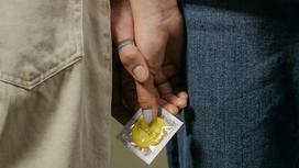 Парень и девушка держат желтый презерватив