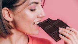 Девушка ест темный шоколад