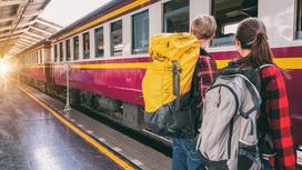 Парень и девушка с рюкзаками на перроне возле поезда
