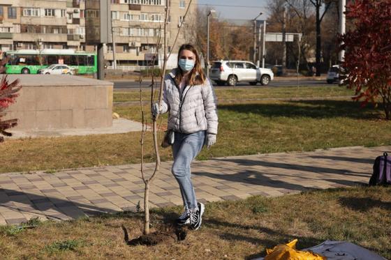 Девушка в серой куртке стоит у дерева Девушка в серой куртке стоит у дерева