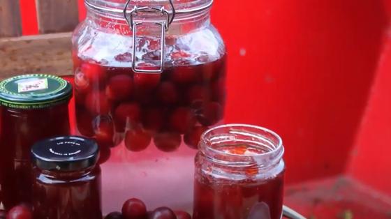 На столе банка с компотом из красных черешен и маленькие банки с вареньем На столе банка с компотом из красных черешен и маленькие банки с вареньем