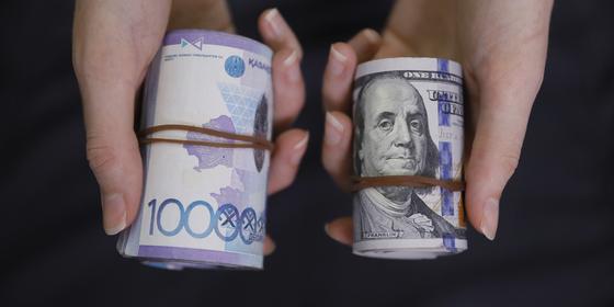 Женщина держит в руках тенге и доллары Женщина держит в руках тенге и доллары