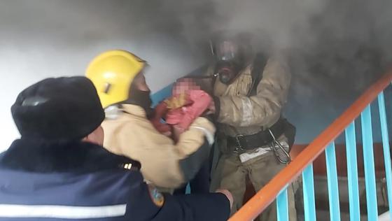 Спасатели выносят ребенка из дома по лестнице Спасатели выносят ребенка из дома по лестнице