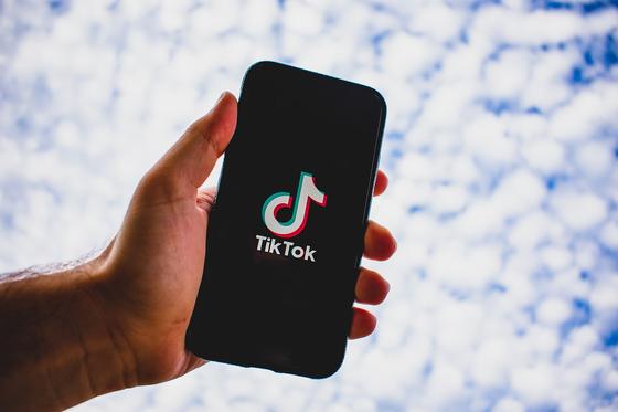 Мужчина держит в руке телефон с приложением TikTok Мужчина держит в руке телефон с приложением TikTok