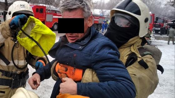 Пожарные выносят мужчину в синей куртке Пожарные выносят мужчину в синей куртке