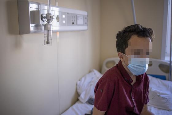 Мальчик сидит на кровати в больнице Мальчик сидит на кровати в больнице