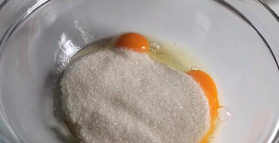 Яйца, смешанные с сахарным песком, в стеклянной миске Яйца, смешанные с сахарным песком, в стеклянной миске