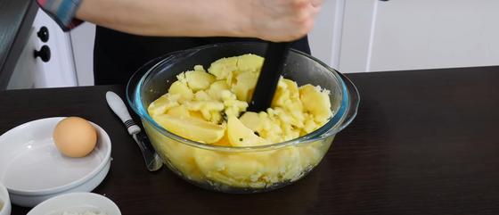 Отваренный картофель в стеклянной миске с толкушкой Отваренный картофель в стеклянной миске с толкушкой
