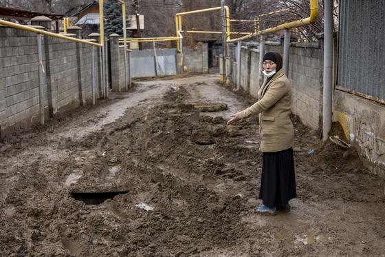 Женщина стоит посреди улицы в грязи Женщина стоит посреди улицы в грязи