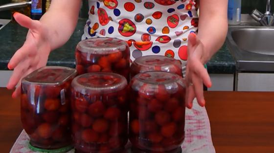 Перевернутые банки с компотом из черешен стоят на столе Перевернутые банки с компотом из черешен стоят на столе