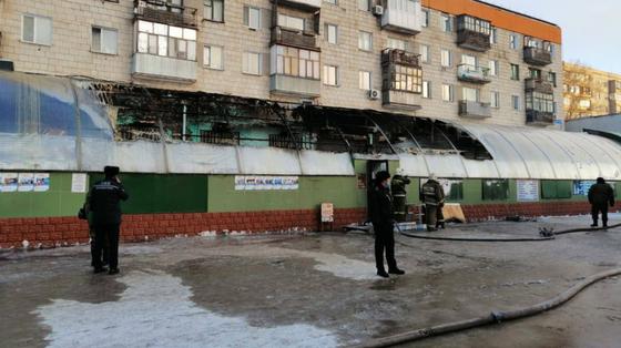 Сотрудники экстренных служб стоят возле горевшего здания магазина Сотрудники экстренных служб стоят возле горевшего здания магазина