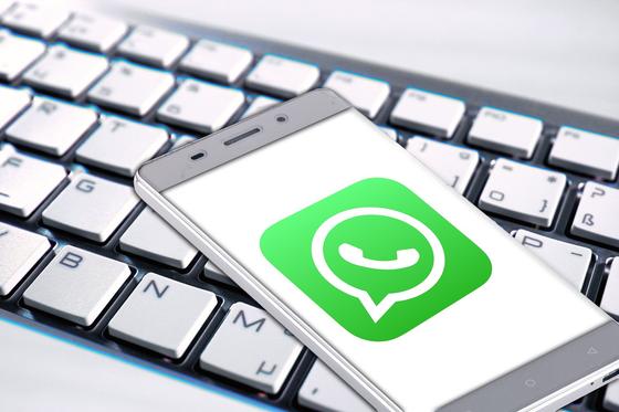 Смартфон с иконкой WhatsApp лежит на клавиатуре Смартфон с иконкой WhatsApp лежит на клавиатуре